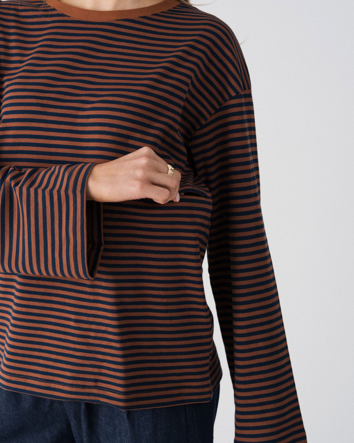 Model opening the hidden two-way underbust zip on the Lenelly Lena striped tee in brown and navy for discreet breastfeeding access