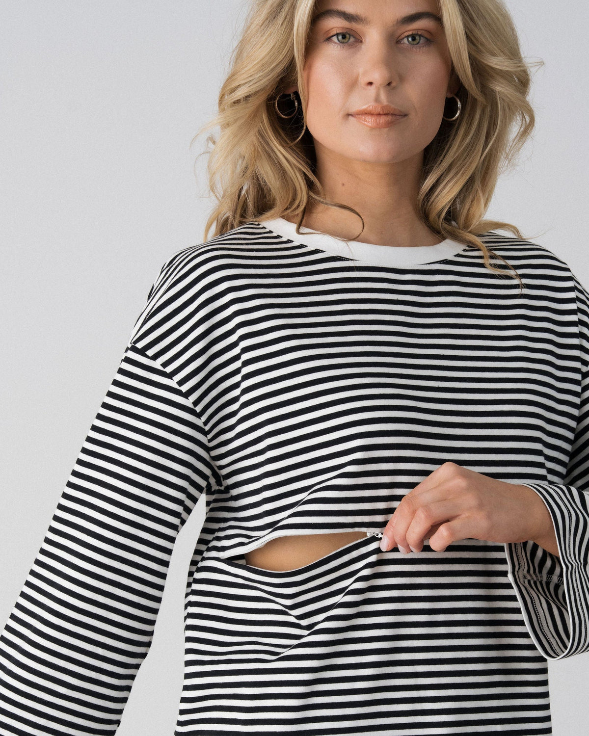 Model opening the hidden two-way underbust zip on the Lenelly Lena striped tee for discreet breastfeeding access