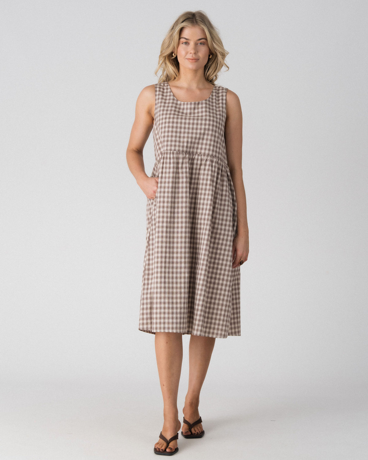 Lenelly Nila nursing dress in beige and brown plaid with hand in the side pocket, front view