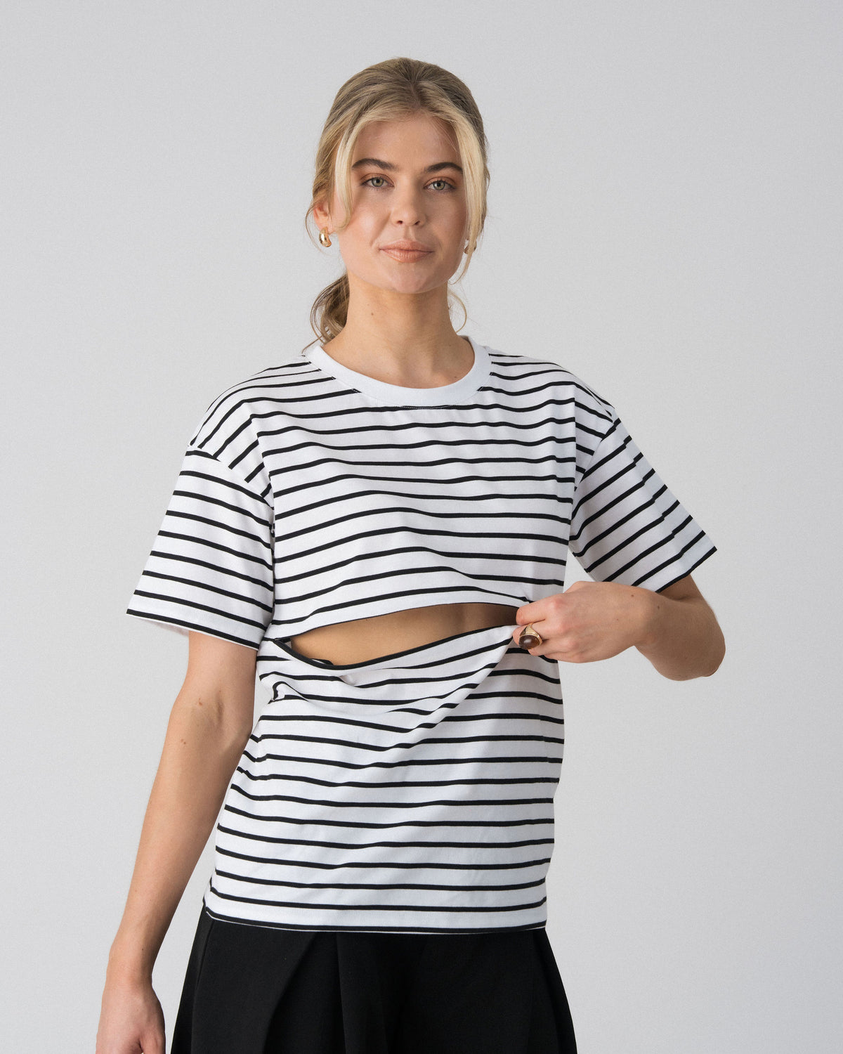 Model opening the hidden two-way underbust zip on the Lenelly Issa striped tee in white and black for discreet breastfeeding access