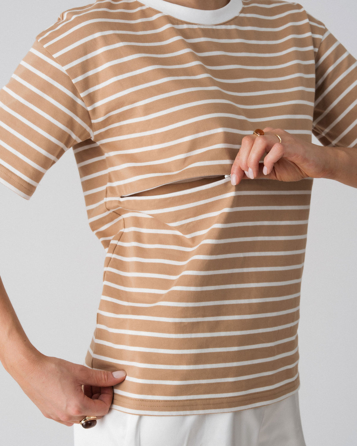 Model opening the hidden two-way underbust zip on the Lenelly Issa striped tee for discreet breastfeeding access
