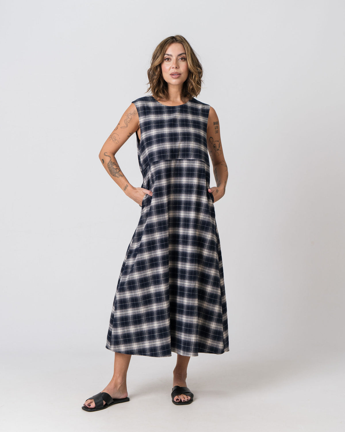 Lenelly Bridget nursing dress in navy and cream plaid with hands in the functional side pockets, front view