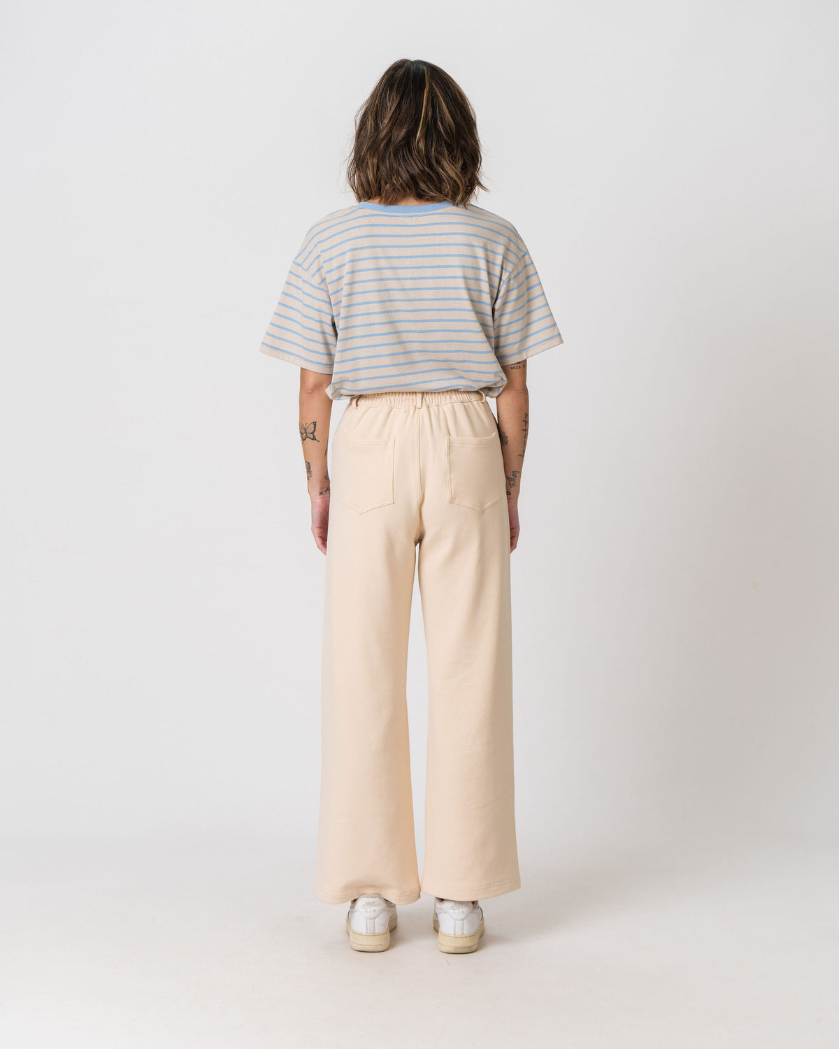Back view of the Lenelly Mish sweatpants in apricot, wide leg postpartum sweatpants worn with a striped tee