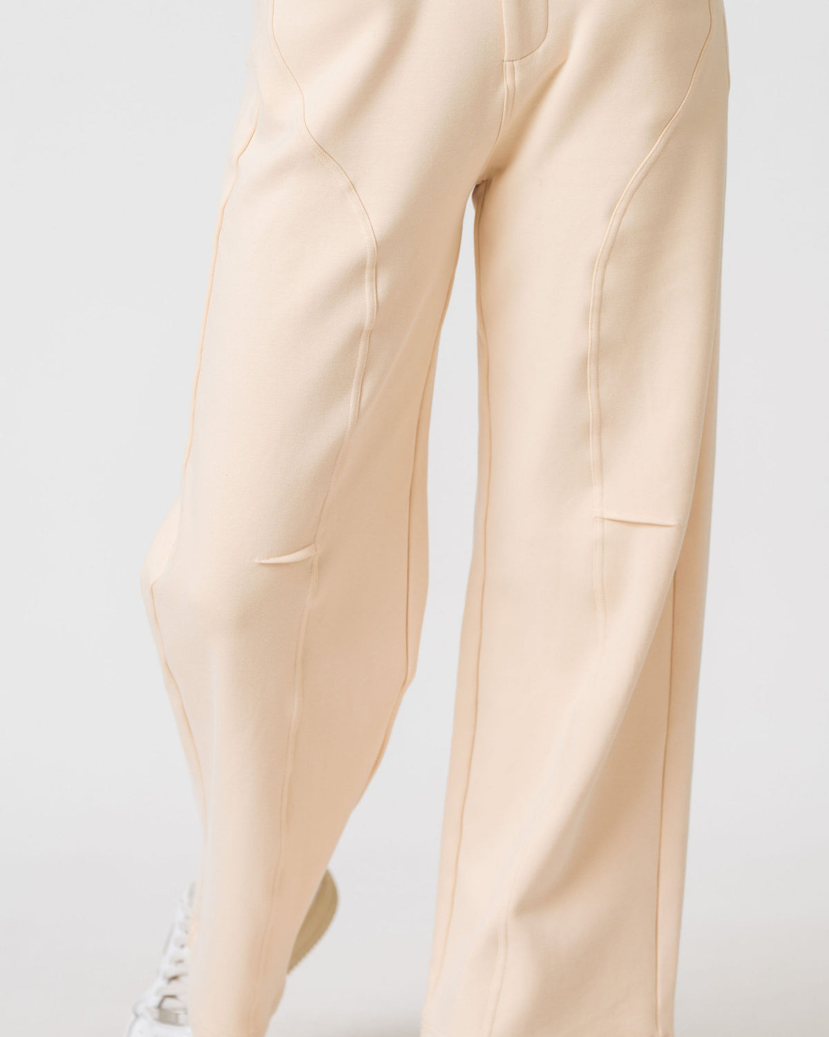 Close-up of the curved seam detailing on the leg of the Lenelly Mish sweatpants in apricot