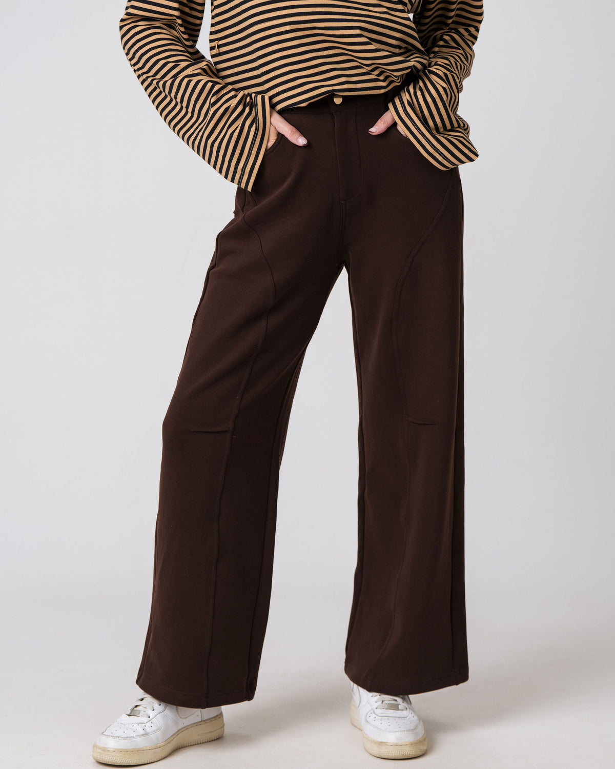 Lenelly Mish postpartum sweatpants in chocolate styled with a striped long sleeve top, cropped front view with hands in the pockets