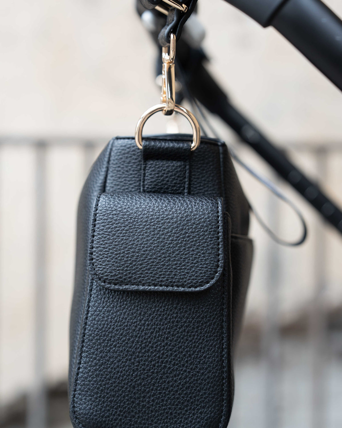 Lenelly Hera pram caddy bag in black vegan leather with adjustable strap, side view attached to a stroller