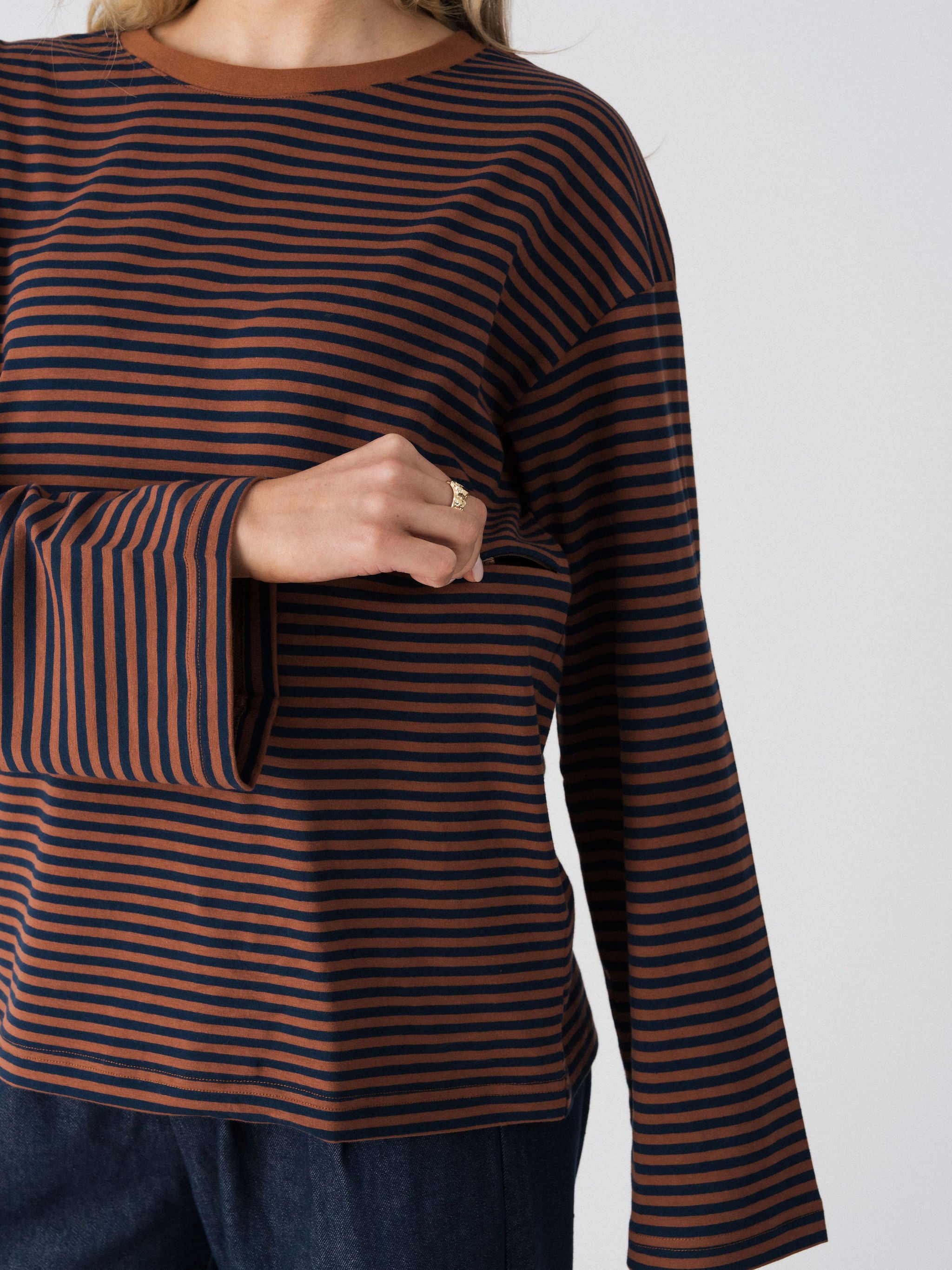 Model opening the hidden two-way underbust zip on the Lenelly Lena striped tee in brown and navy for discreet breastfeeding access