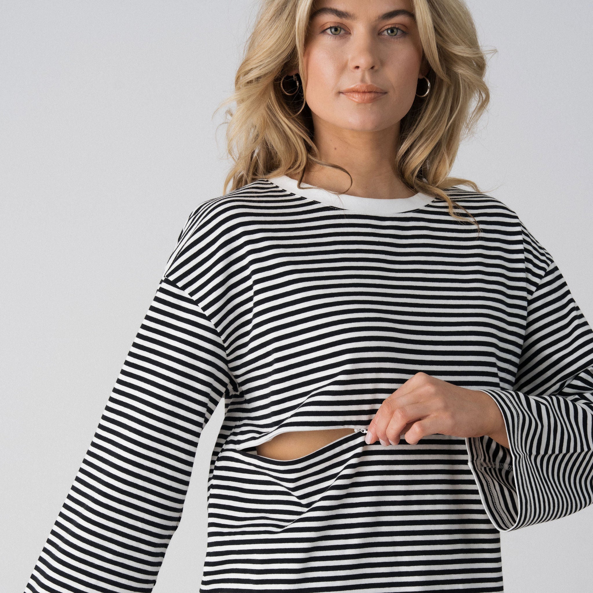 Model opening the hidden two-way underbust zip on the Lenelly Lena striped tee for discreet breastfeeding access