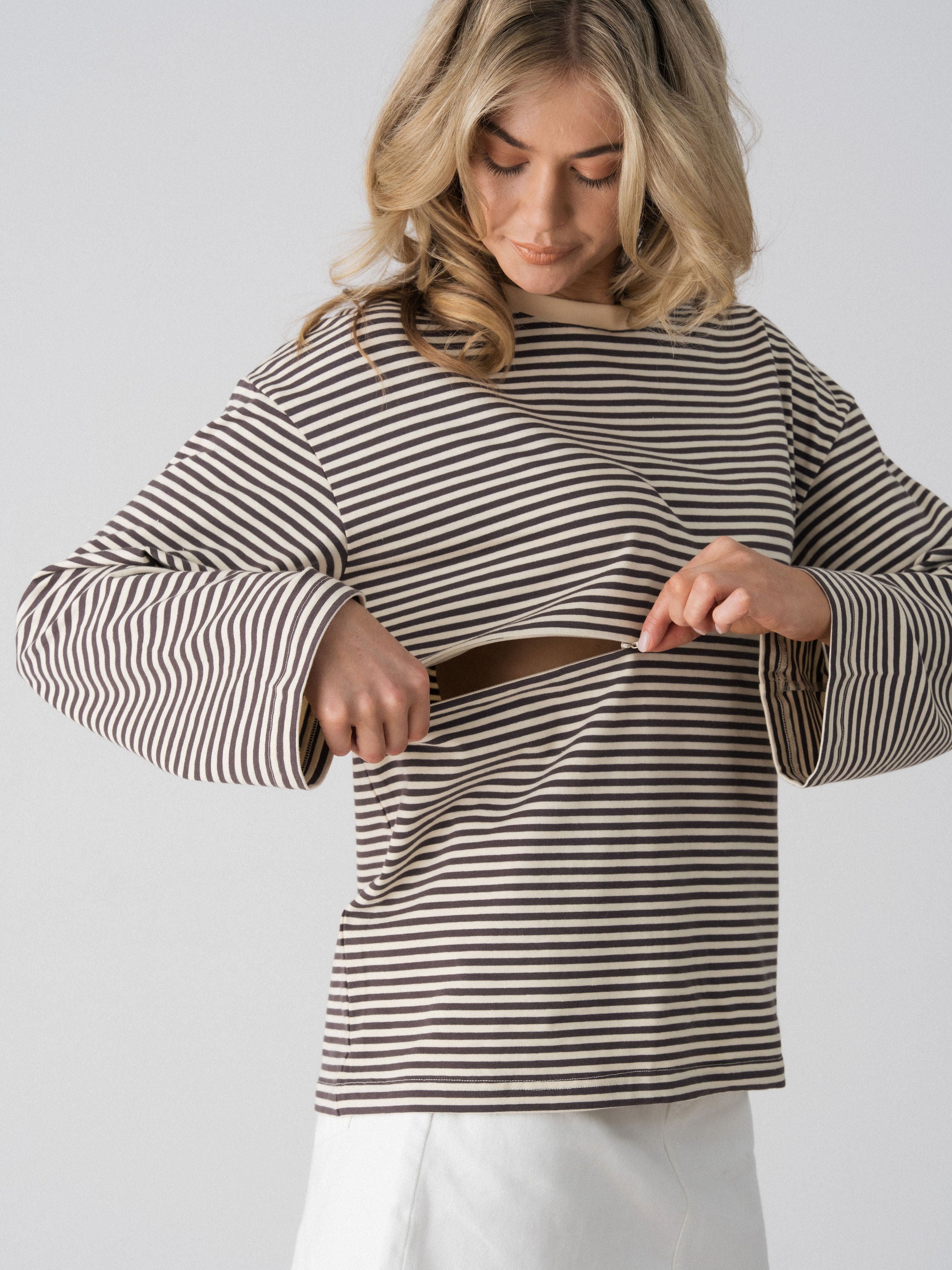 Model opening the hidden two-way underbust zip on the Lenelly Lena striped tee in grey and off-white for discreet breastfeeding access