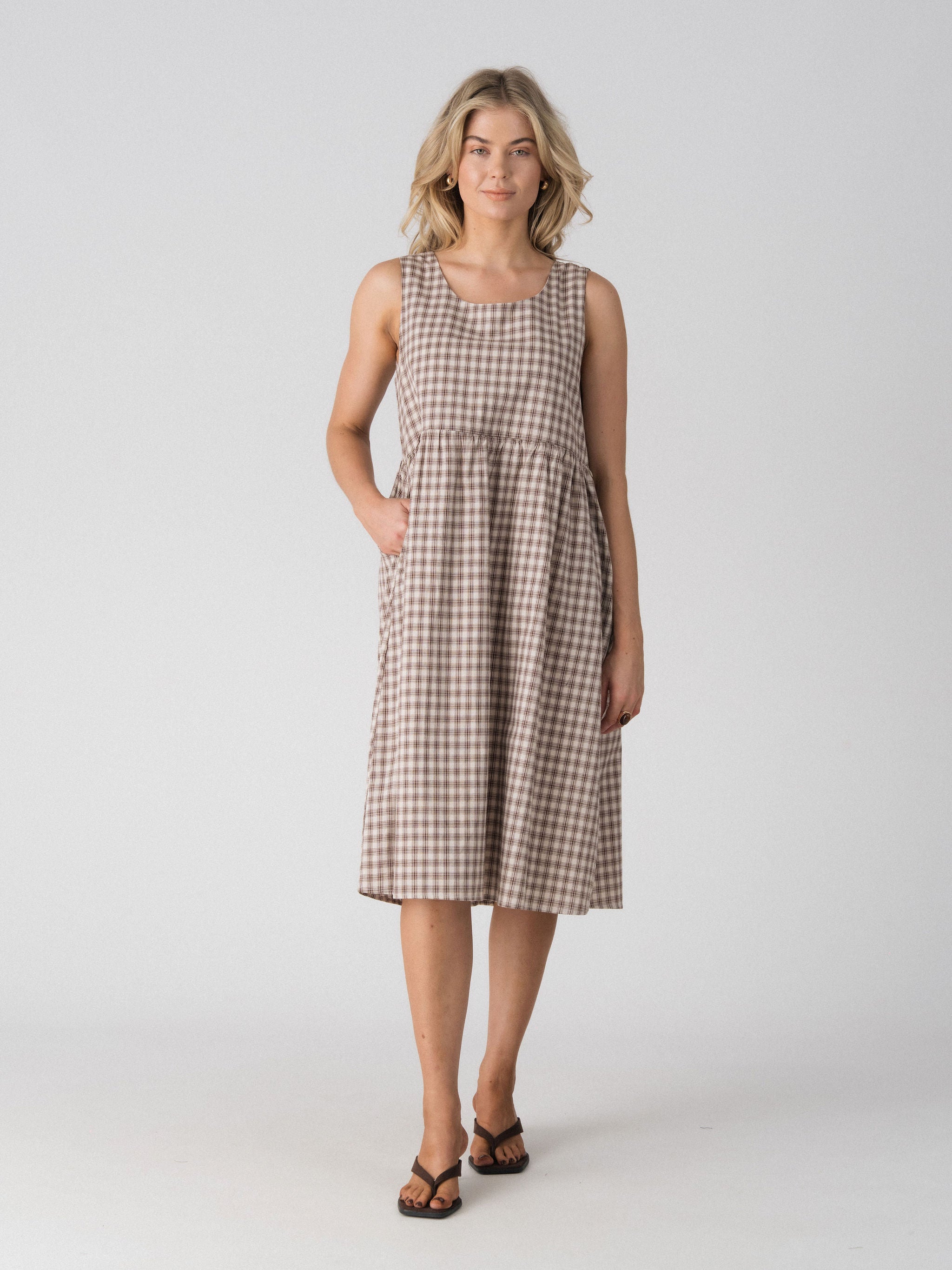Lenelly Nila nursing dress in beige and brown plaid with hand in the side pocket, front view