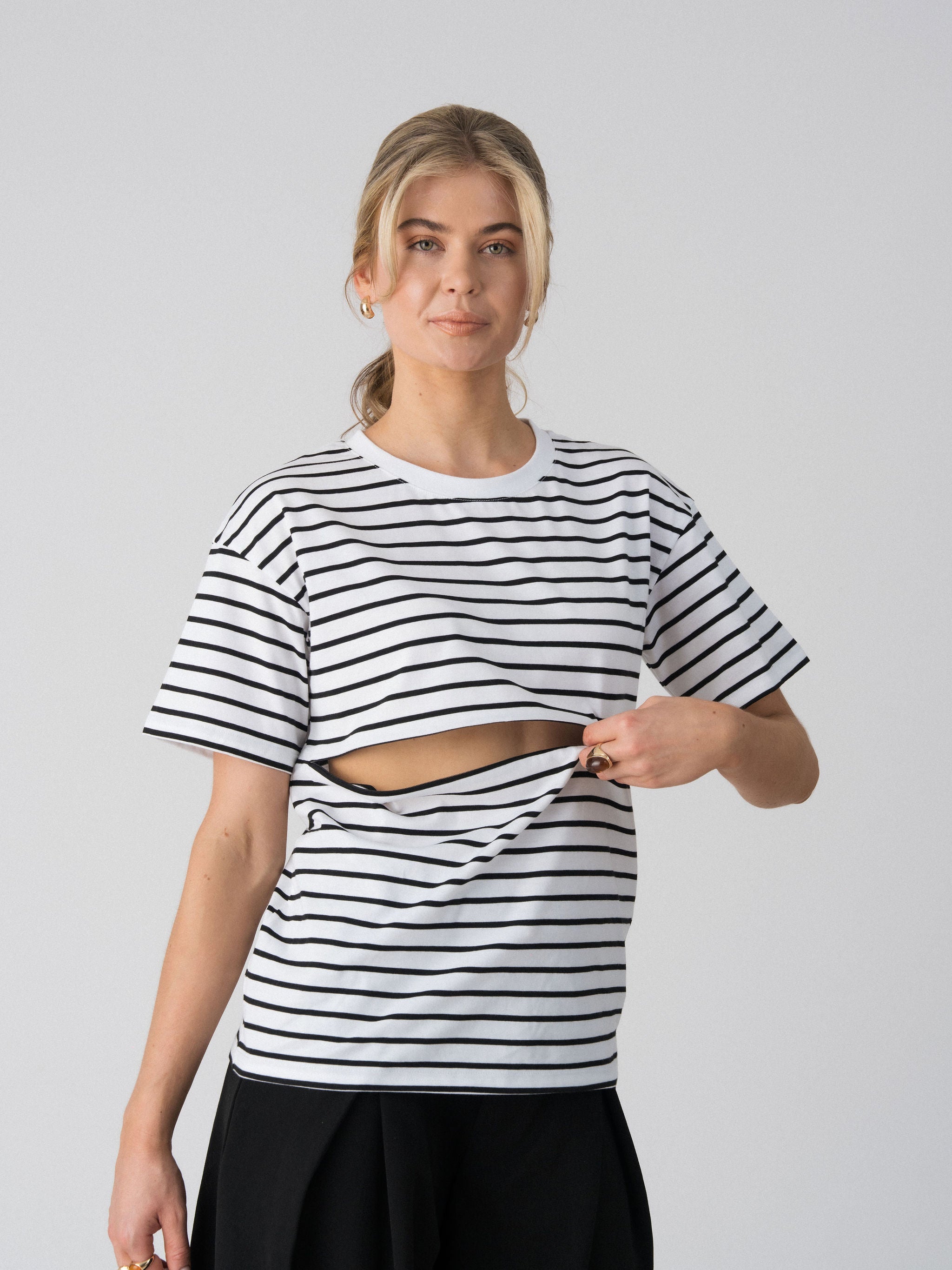 Model opening the hidden two-way underbust zip on the Lenelly Issa striped tee in white and black for discreet breastfeeding access