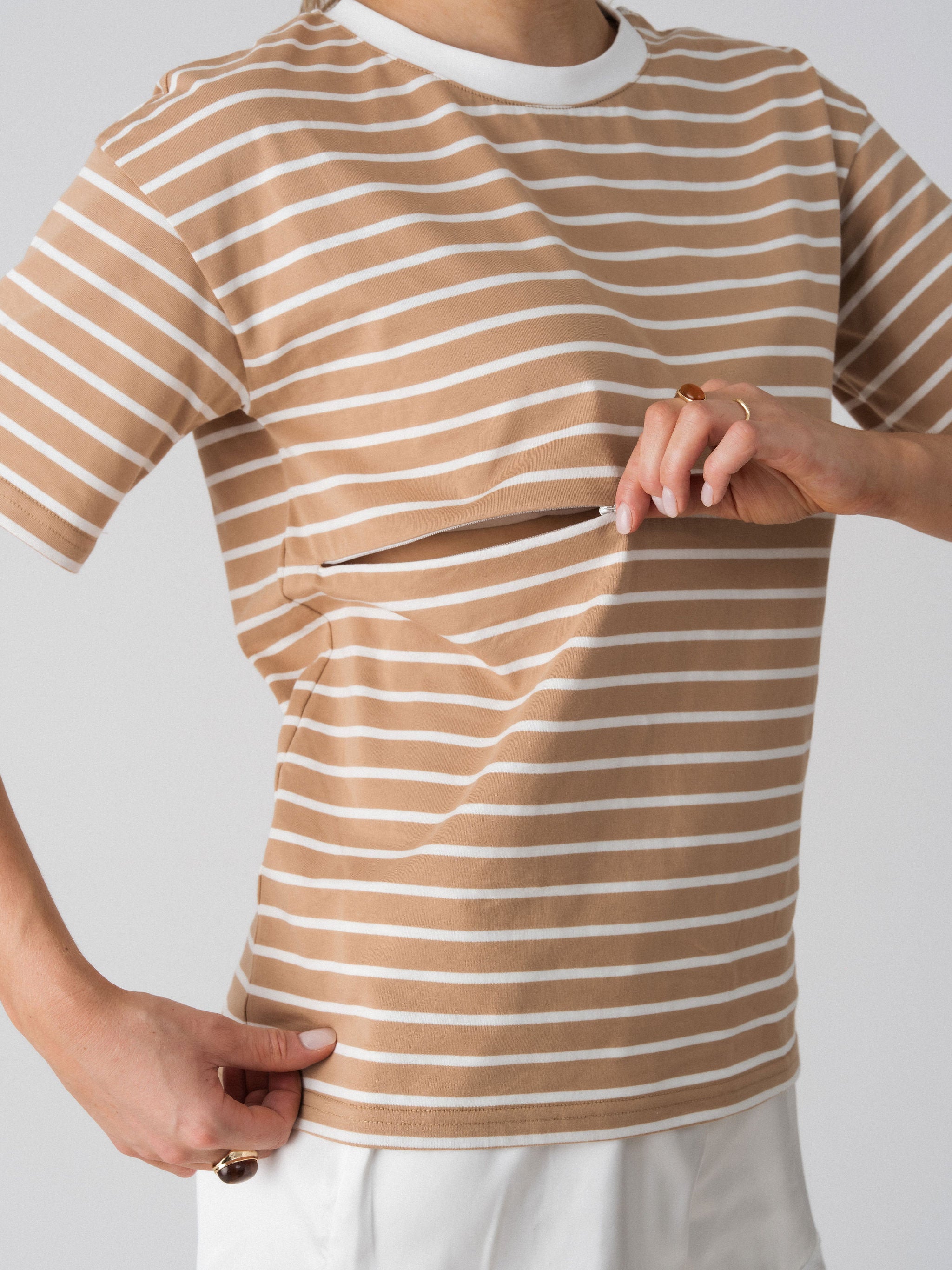 Model opening the hidden two-way underbust zip on the Lenelly Issa striped tee for discreet breastfeeding access