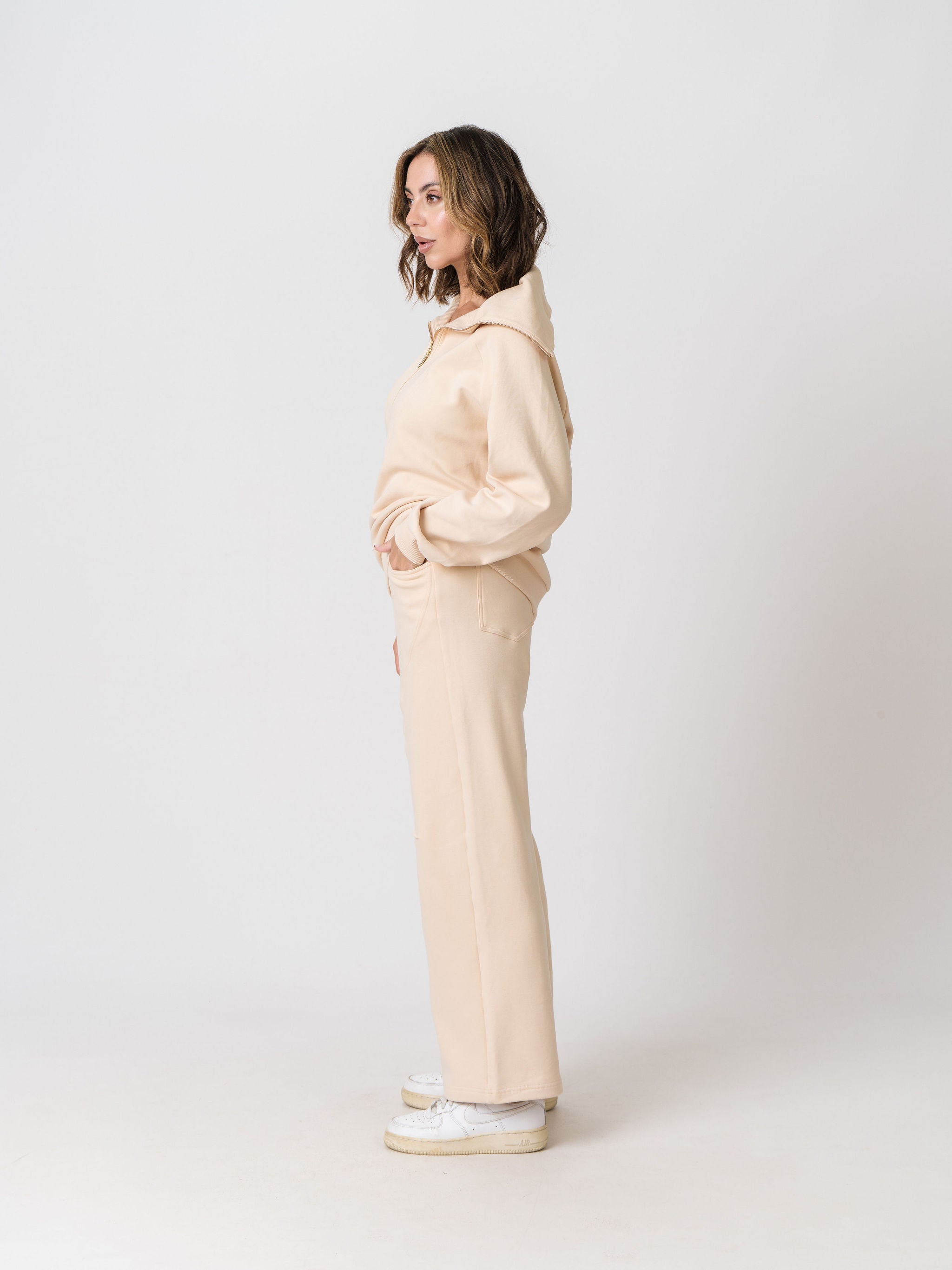Lenelly Mish sweatpants in apricot worn with the matching Mish half zip sweatshirt, side view on a light studio background