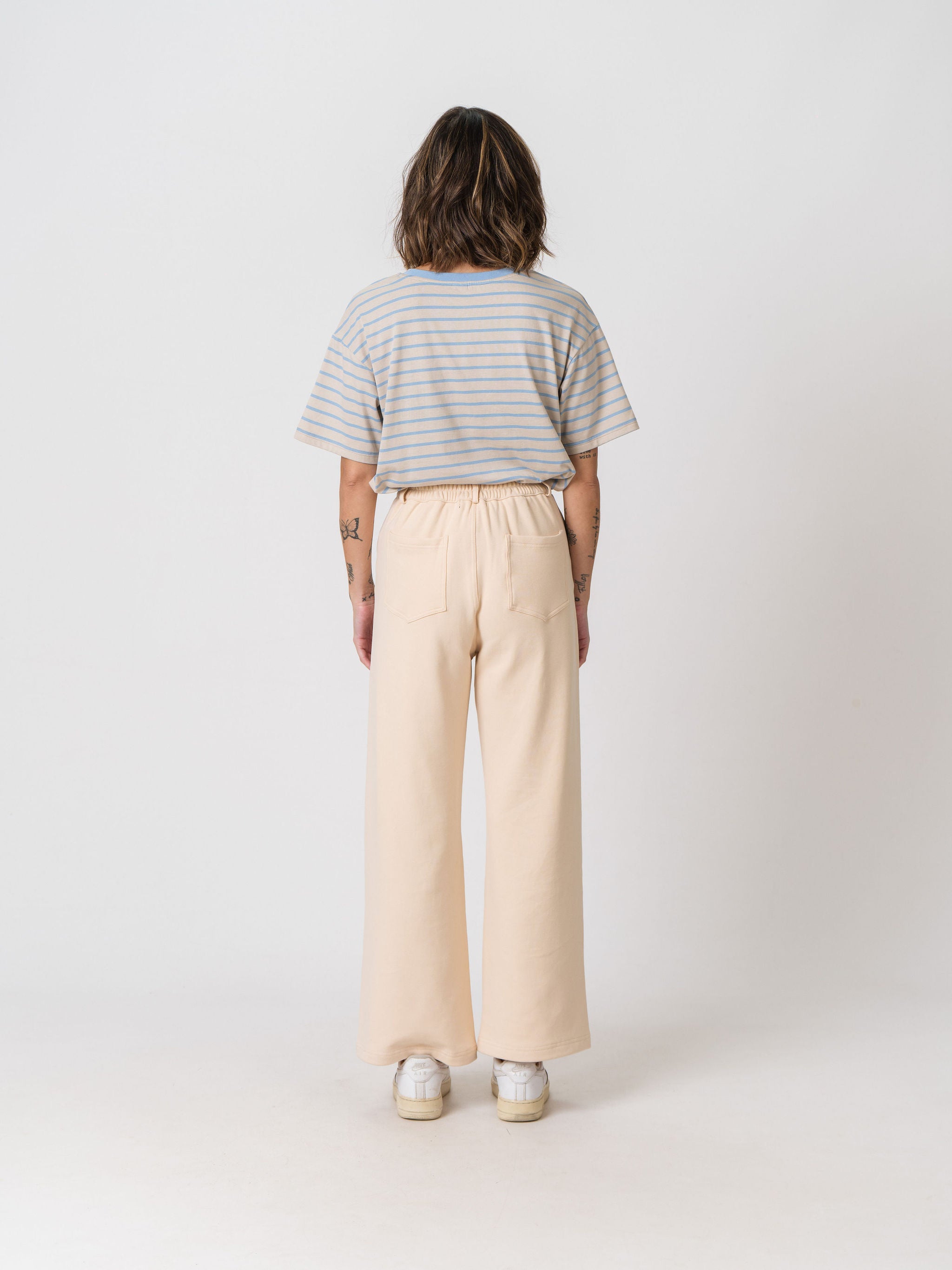 Back view of the Lenelly Mish sweatpants in apricot, wide leg postpartum sweatpants worn with a striped tee