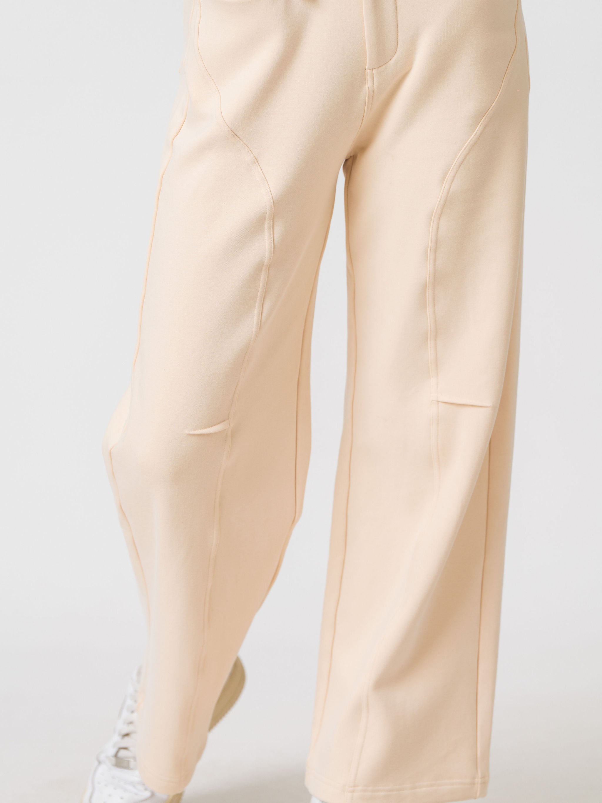 Close-up of the curved seam detailing on the leg of the Lenelly Mish sweatpants in apricot