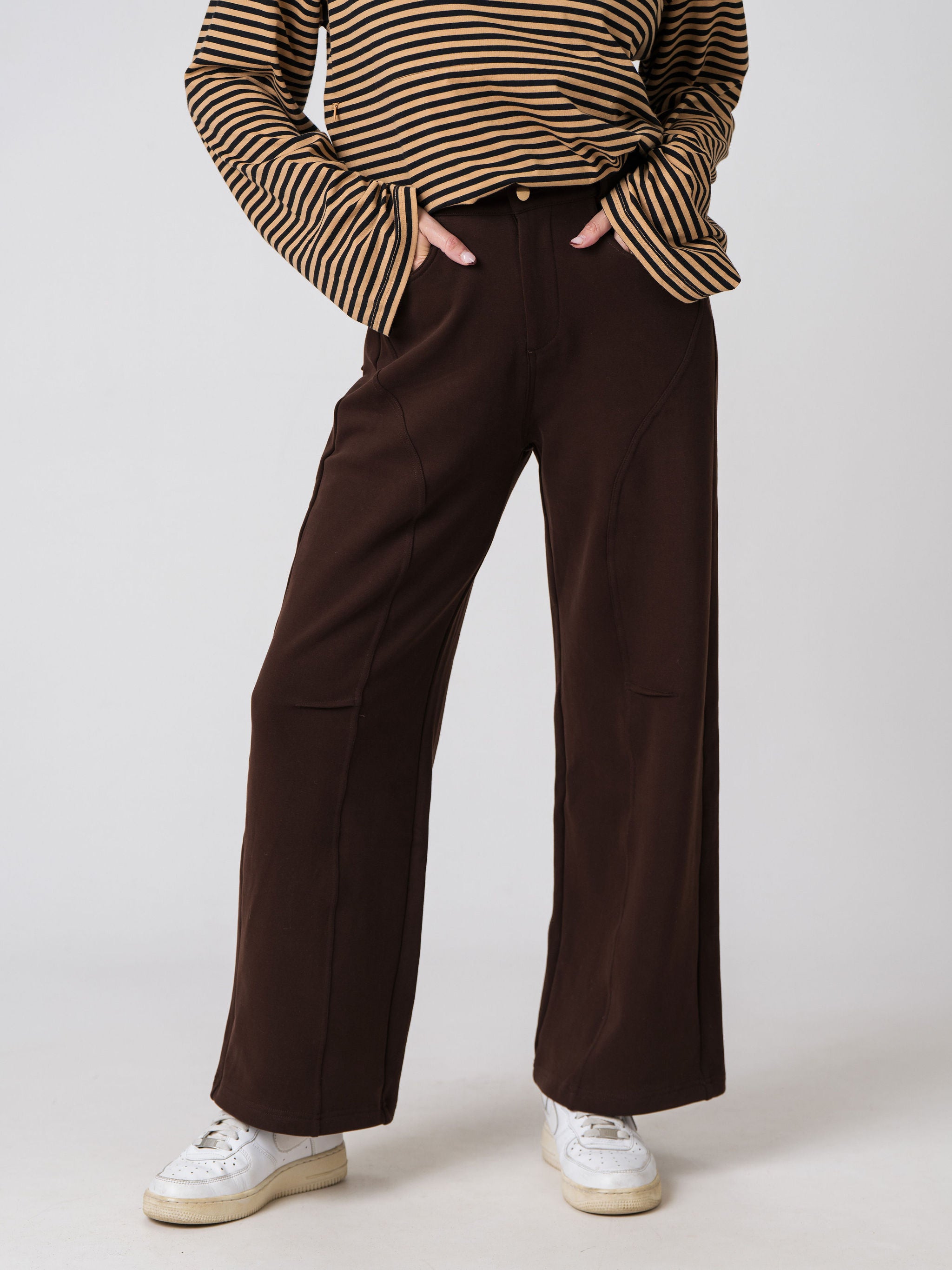 Lenelly Mish postpartum sweatpants in chocolate styled with a striped long sleeve top, cropped front view with hands in the pockets