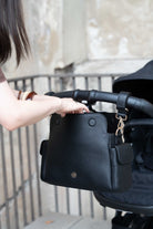 Lenelly Hera pram caddy bag in black vegan leather with adjustable strap, front view attached to a stroller